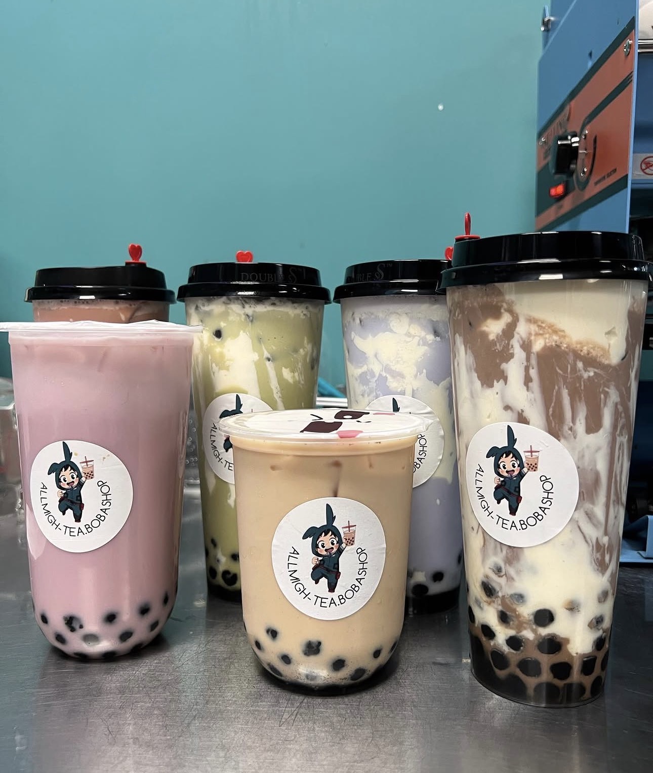 Lineup of colorful boba drinks with All Migh-Tea stickers